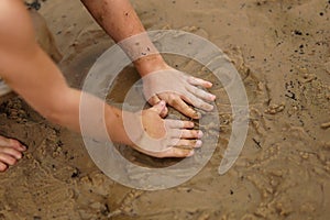 Hands of Young Child Playing in Wet Sand at the Beach