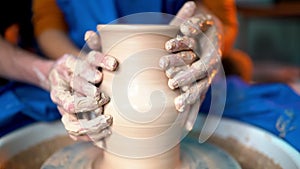 Hands of young couple in love making clay jug on potter`s wheel. Sensual footage of people on romantic date. Pottery