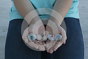 hands of young female hold gray round stones with letters on them and inscription relax.