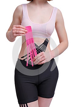 Hands of young girl applying pink kinesiology tape on the her abdomen