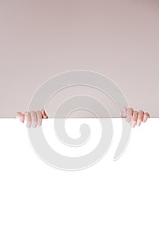 Hands of young girl behind white empty banner. Free copyspace area. Horizontal image