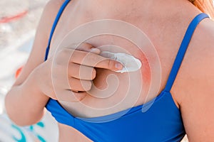 The hands of a young girl, in a blue swimsuit and shorts are going to smear on themselves a cream for sunbathing and protection