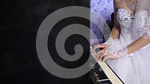 Hands of a young girl playing the instrument keyboard clave. girl in a white dress playing for the black piano. The photo