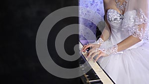 Hands of a young girl playing the instrument keyboard clave. girl in a white dress playing for the black piano. The photo