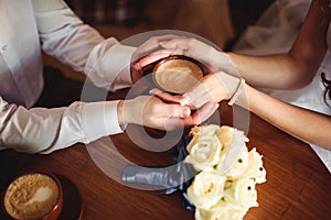 Hands of young lovers holding a hot cup coffee