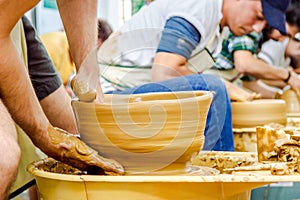 Hands of a young man creating a clay jar on a potter's wheel