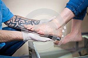 The hands of a young man doctor orthopedist conducts diagnostics, foot foot test of a woman, for the manufacture of individual,