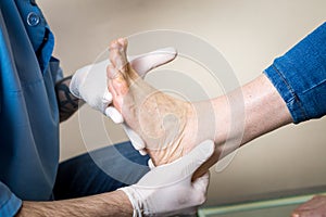The hands of a young man doctor orthopedist conducts diagnostics, foot foot test of a woman, for the manufacture of individual, or