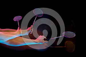 The hands of young man playing badminton over black background