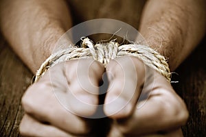 The hands of a young man tied with rope