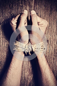 The hands of a young man tied with rope