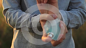 Hands of a young man using perfume at sunset