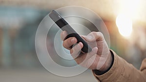 Hands of young man using smartphone in the street near shopping mall. Communication, online shopping, chat, social