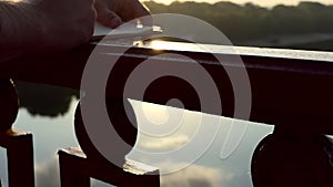 Hands of a Young Man Write Something on a River Bridge at Sunset in Slo-Mo