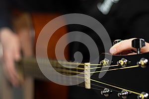 The hands of a young musician playing an acoustic guitar with metal strings close-up with a blurred background