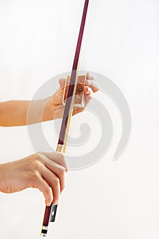 Hands of a young violinist rosin his bow on a light background, vertical