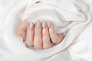Hands of a young woman with beige nails on a white background. Manicure
