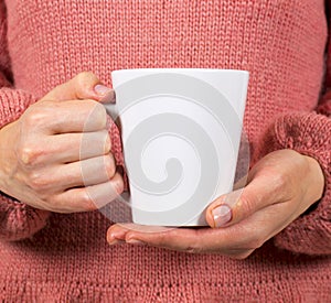 Hands of a young woman holding a Cup of coffee or tea.