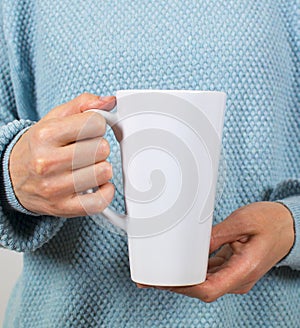 Hands of a young woman holding a Cup of coffee or tea.