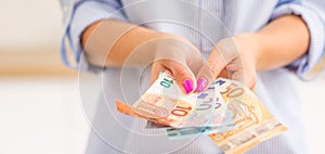 Hands of young woman holding euro banknotes