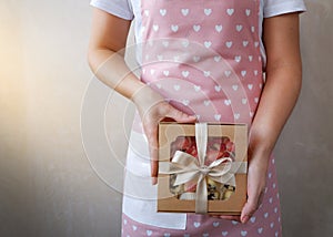 Hands of a young woman holding a gift with sweets