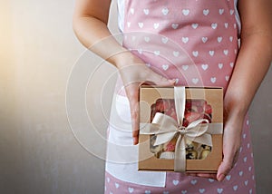 Hands of a young woman holding a gift with sweets