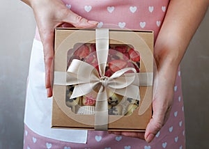 Hands of a young woman holding a gift with sweets