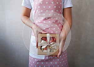 Hands of a young woman holding a gift with sweets