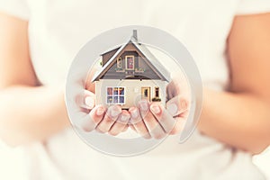 Hands of young woman holding model house