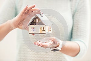 Hands of young woman holding model house