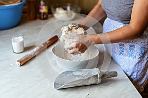 Hands of a young woman, kneading dough to make bread or pizza at home. Production of flour products. Making dough by
