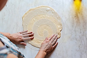 Hands of a young woman, kneading dough to make bread or pizza at home. Production of flour products. Making dough by