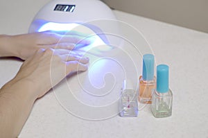 Hands of young woman at manicure procedure close up on white background