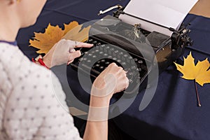 Hands of young woman, office worker, are typing text letter on old retro typewriter.