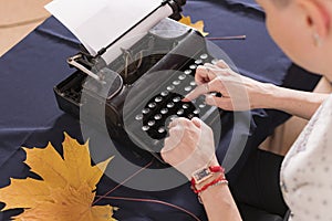 Hands of young woman, office worker, are typing text letter on old retro typewriter.