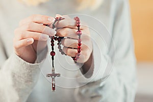 Hands young woman prays to God, folded her arms on her chest uses a rosary and a crucifix