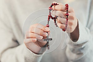 Hands young woman prays to God, folded her arms on her chest uses a rosary and a crucifix