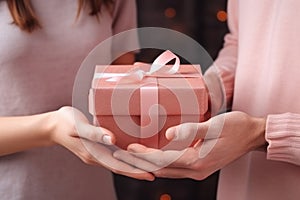 Hands young woman receiving gift box from hands loving man, surprise on Valentines Day