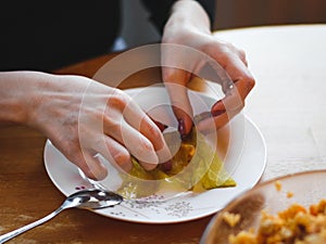 The hands of a young woman roll up a raw sauerkraut leaf with meat and rice filling in a plate
