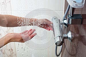 Hands of a young woman taking a hot shower