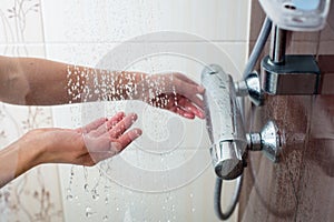 Hands of a young woman taking a hot shower photo