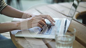 Hands of young woman using touchpad and typing outdoors