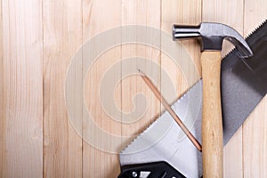 Handsaw, claw hammer and pencil on wooden desk background