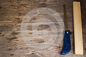 Handsaw over a wooden boards background