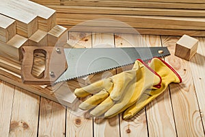 Handsaw and yellow working gloves on wooden timber materials