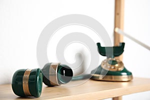 Handset and green vintage corded phone on wooden shelf near white wall, closeup