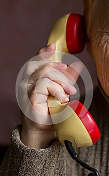 The handset is in the hand of an old woman.