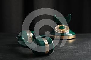 Handset and vintage corded phone on black stone table, closeup