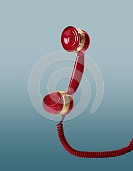 Handset of vintage red corded telephone flying in air on light blue background