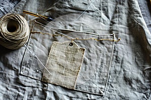 handsewn tag on a linen apron, needle and thread in frame